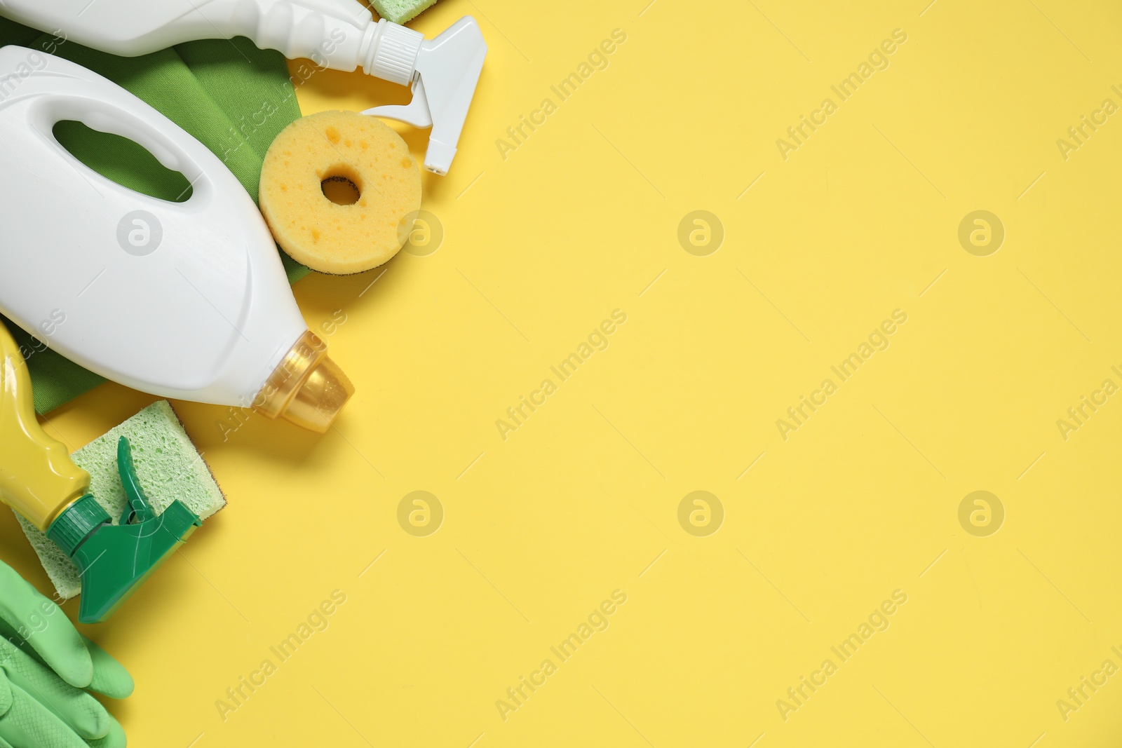 Photo of Detergents and supplies on yellow background, flat lay. Space for text