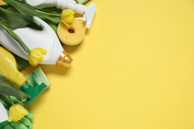 Photo of Spring cleaning. Detergents, supplies and tulips on yellow background, flat lay. Space for text