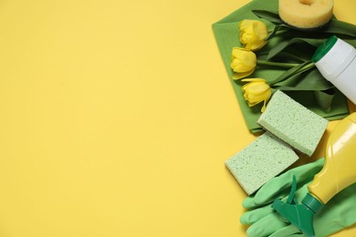 Photo of Spring cleaning. Detergents, supplies and tulips on yellow background, flat lay. Space for text