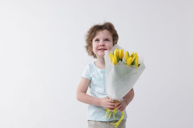 Photo of Cute little boy with bouquet of tulips on white background