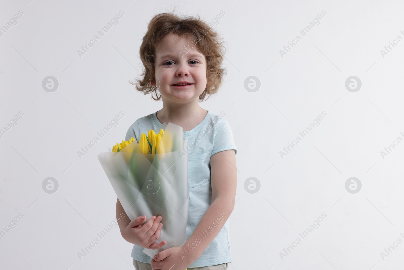 Photo of Cute little boy with bouquet of tulips on white background