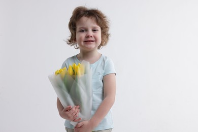 Photo of Cute little boy with bouquet of tulips on white background