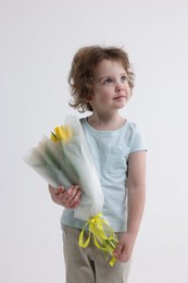 Photo of Cute little boy with bouquet of tulips on white background