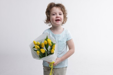 Photo of Cute little boy with bouquet of tulips on white background