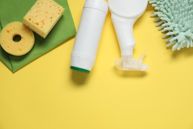 Photo of Detergents and supplies on yellow background, flat lay. Space for text