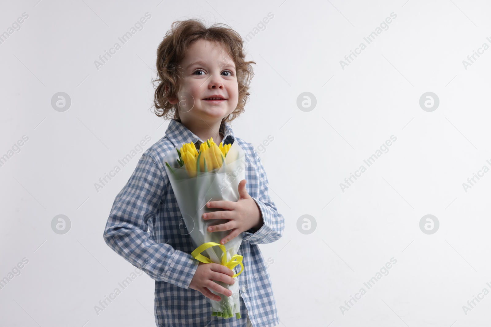 Photo of Cute little boy with bouquet of tulips on white background. Space for text