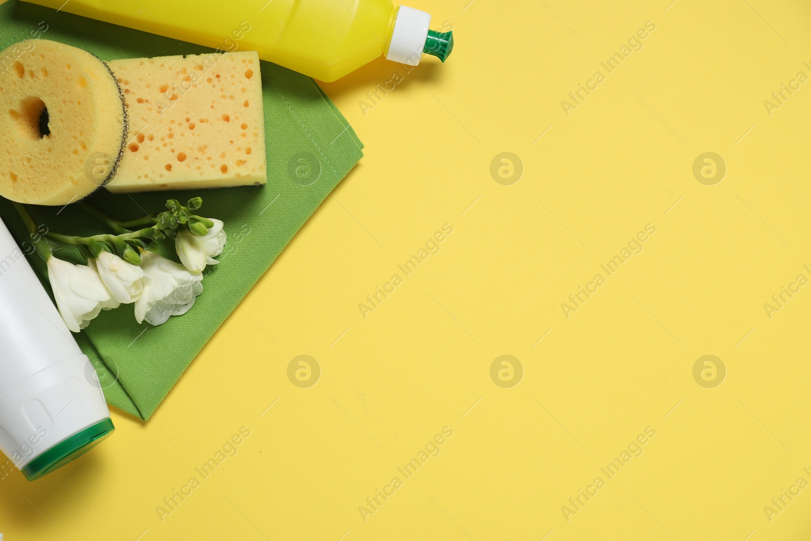 Photo of Spring cleaning. Detergents, supplies and flowers on yellow background, flat lay. Space for text