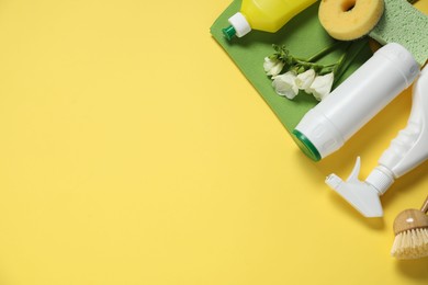 Photo of Spring cleaning. Detergents, supplies and flowers on yellow background, flat lay. Space for text