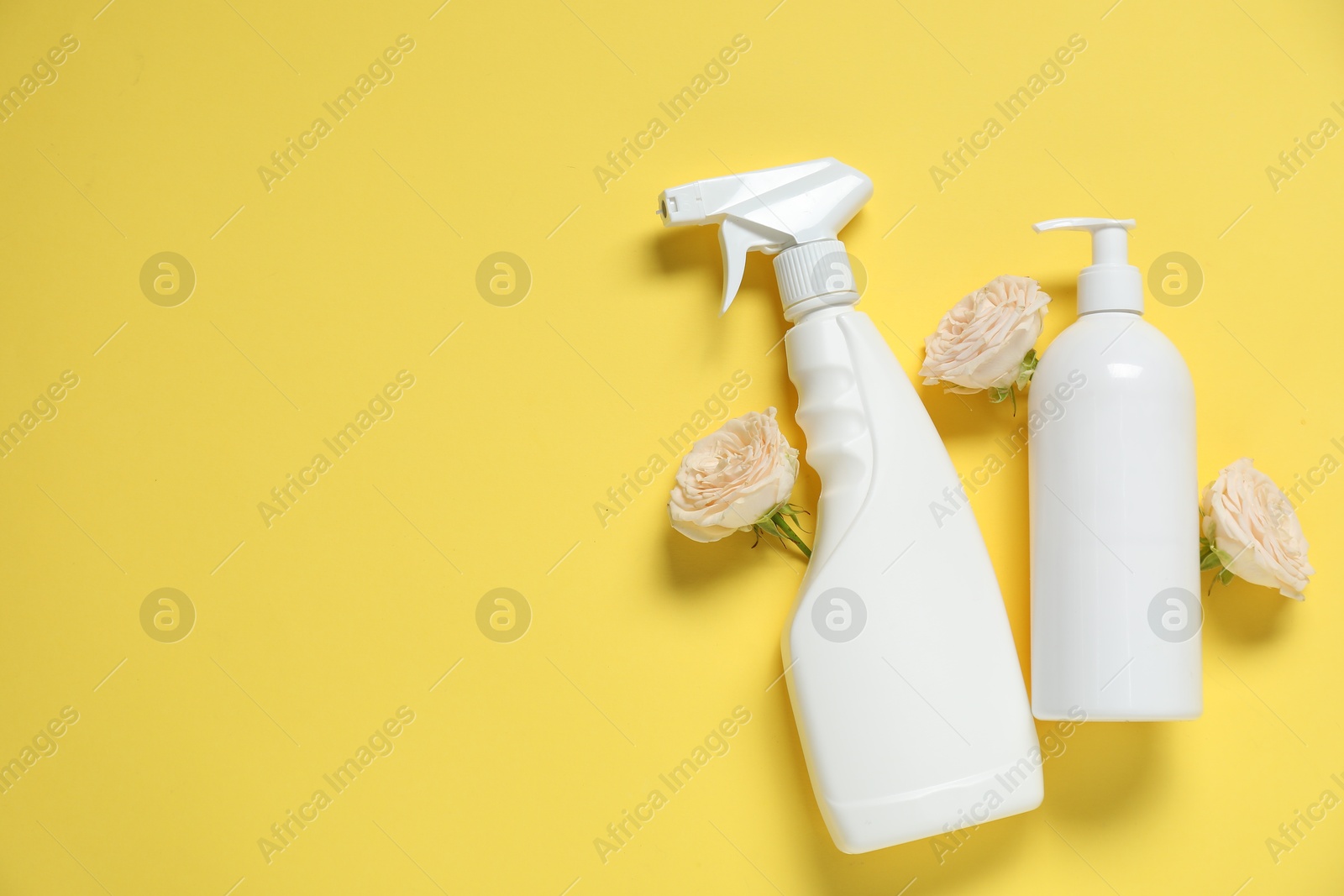 Photo of Spring cleaning. Detergents and flowers on yellow background, flat lay. Space for text