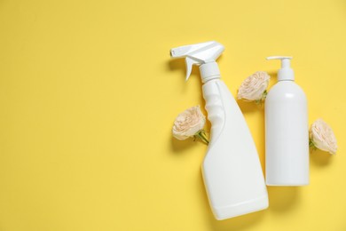 Photo of Spring cleaning. Detergents and flowers on yellow background, flat lay. Space for text