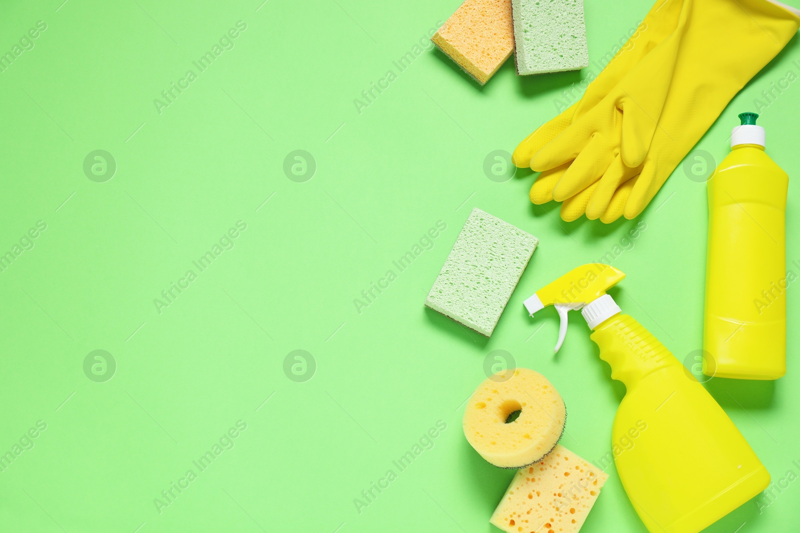 Photo of Detergents and supplies on green background, flat lay. Space for text