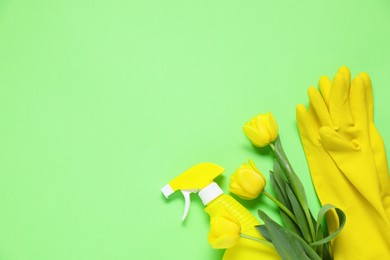 Photo of Spring cleaning. Detergent, gloves and tulips on green background, flat lay. Space for text