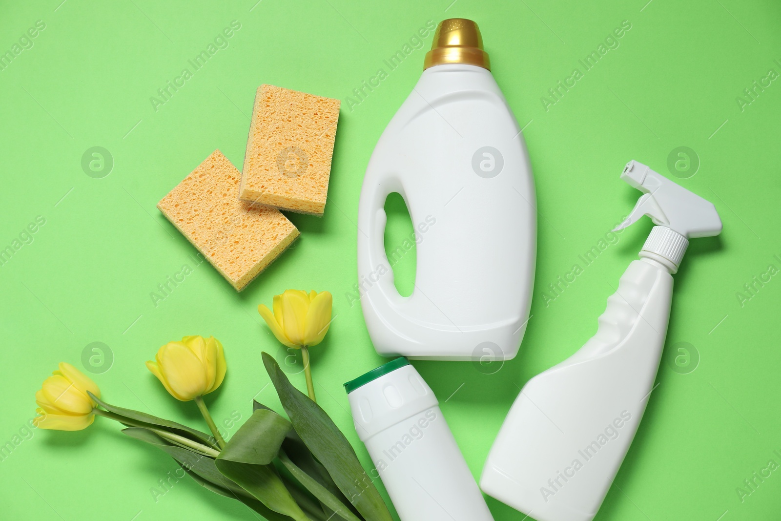 Photo of Spring cleaning. Detergents, sponges and tulips on green background, flat lay