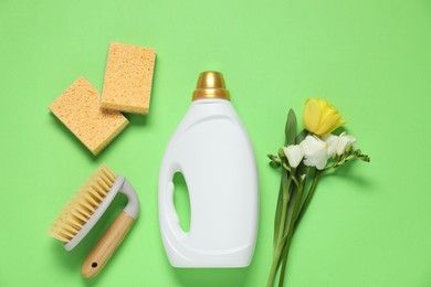 Photo of Spring cleaning. Detergent, supplies and flowers on green background, flat lay