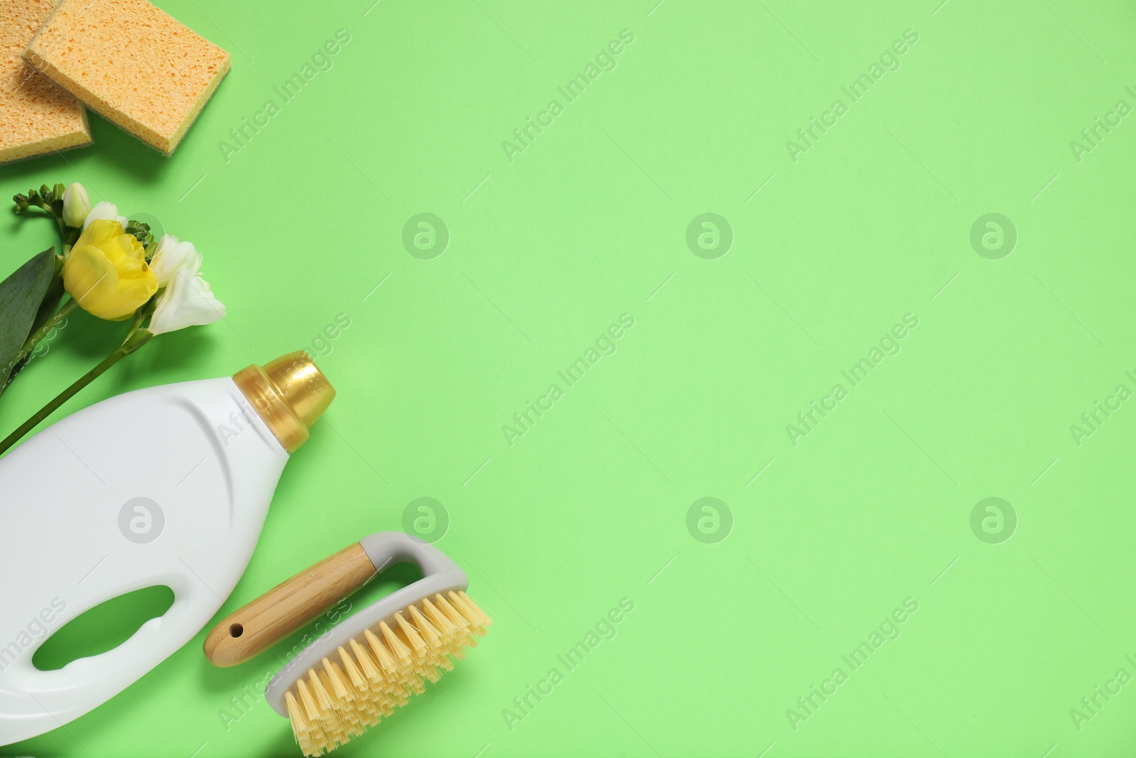 Photo of Spring cleaning. Detergent, supplies and flowers on green background, flat lay. Space for text