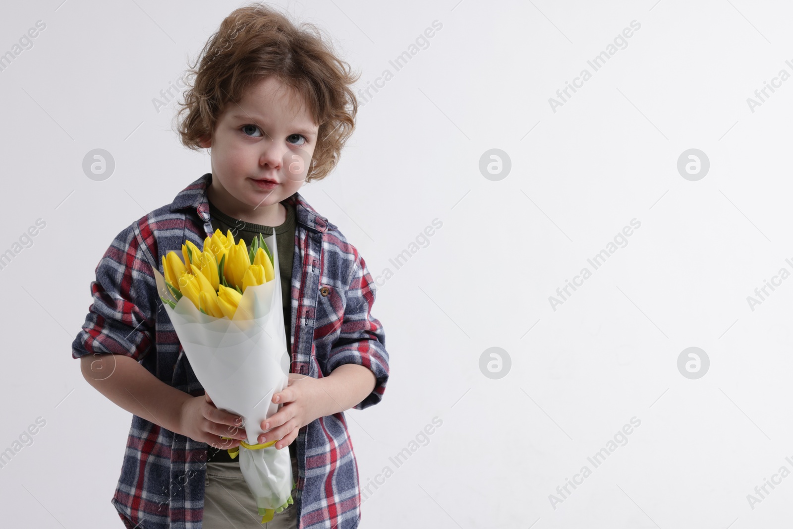 Photo of Cute little boy with bouquet of tulips on white background. Space for text