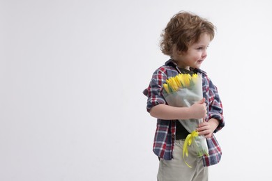 Photo of Cute little boy with bouquet of tulips on white background. Space for text