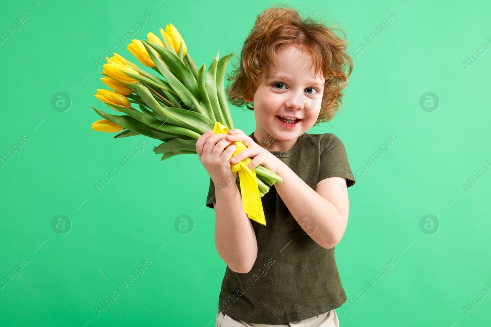 Photo of Cute little boy with bouquet of tulips on green background