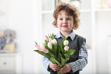 Photo of Cute little boy with bouquet of tulips at home