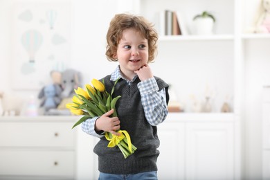 Photo of Cute little boy with bouquet of tulips at home