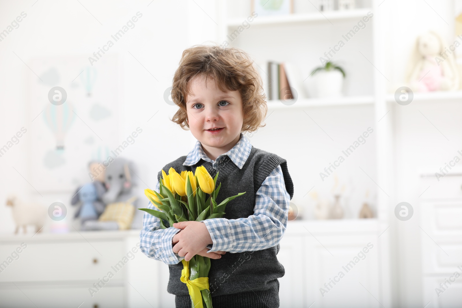 Photo of Cute little boy with bouquet of tulips at home