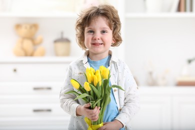 Cute little boy with bouquet of tulips at home