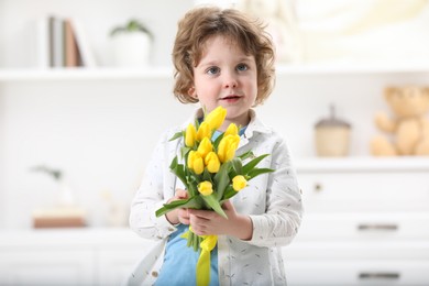 Photo of Cute little boy with bouquet of tulips at home