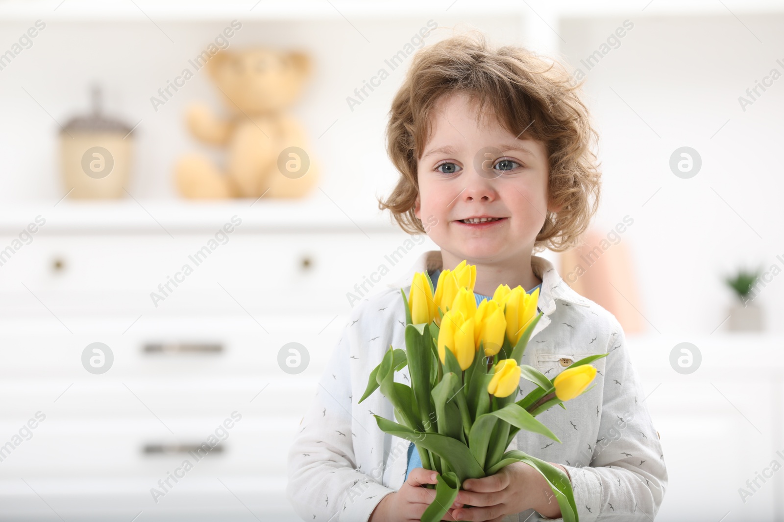 Photo of Cute little boy with bouquet of tulips at home. Space for text