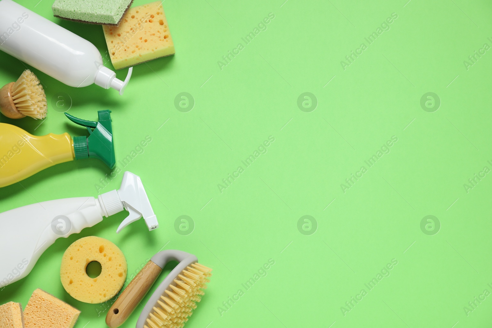 Photo of Detergents and supplies on green background, flat lay. Space for text