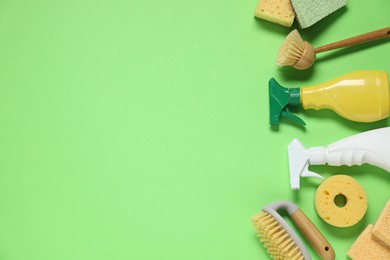 Photo of Detergents and supplies on green background, flat lay. Space for text