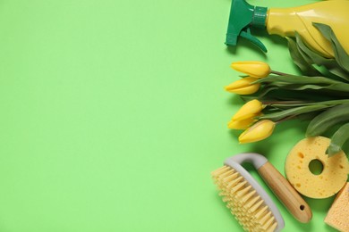 Photo of Spring cleaning. Detergent, supplies and tulips on green background, flat lay. Space for text