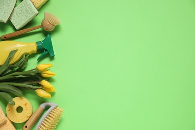 Photo of Spring cleaning. Detergent, supplies and tulips on green background, flat lay. Space for text