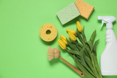 Photo of Spring cleaning. Detergent, supplies and tulips on green background, flat lay. Space for text