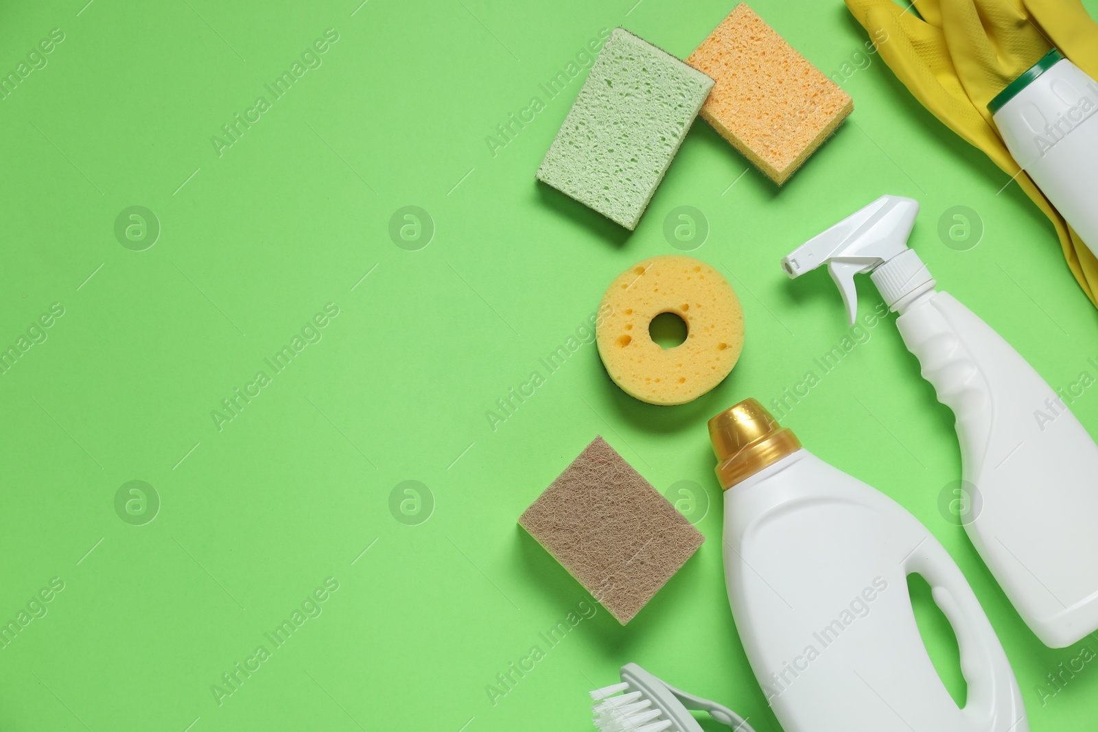 Photo of Detergents and supplies on green background, flat lay. Space for text