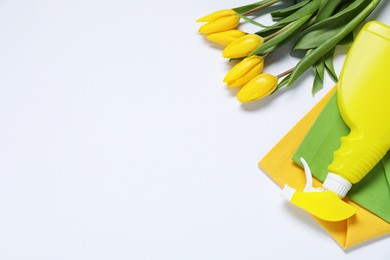 Spring cleaning. Detergent, rags and tulips on white background, flat lay. Space for text