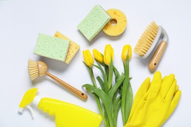 Photo of Spring cleaning. Detergent, supplies and tulips on white background, flat lay