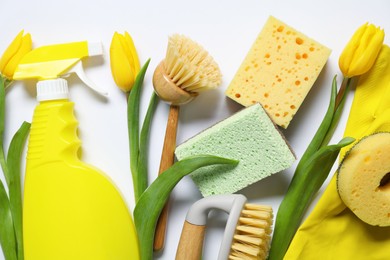 Photo of Spring cleaning. Detergent, supplies and tulips on white background, flat lay