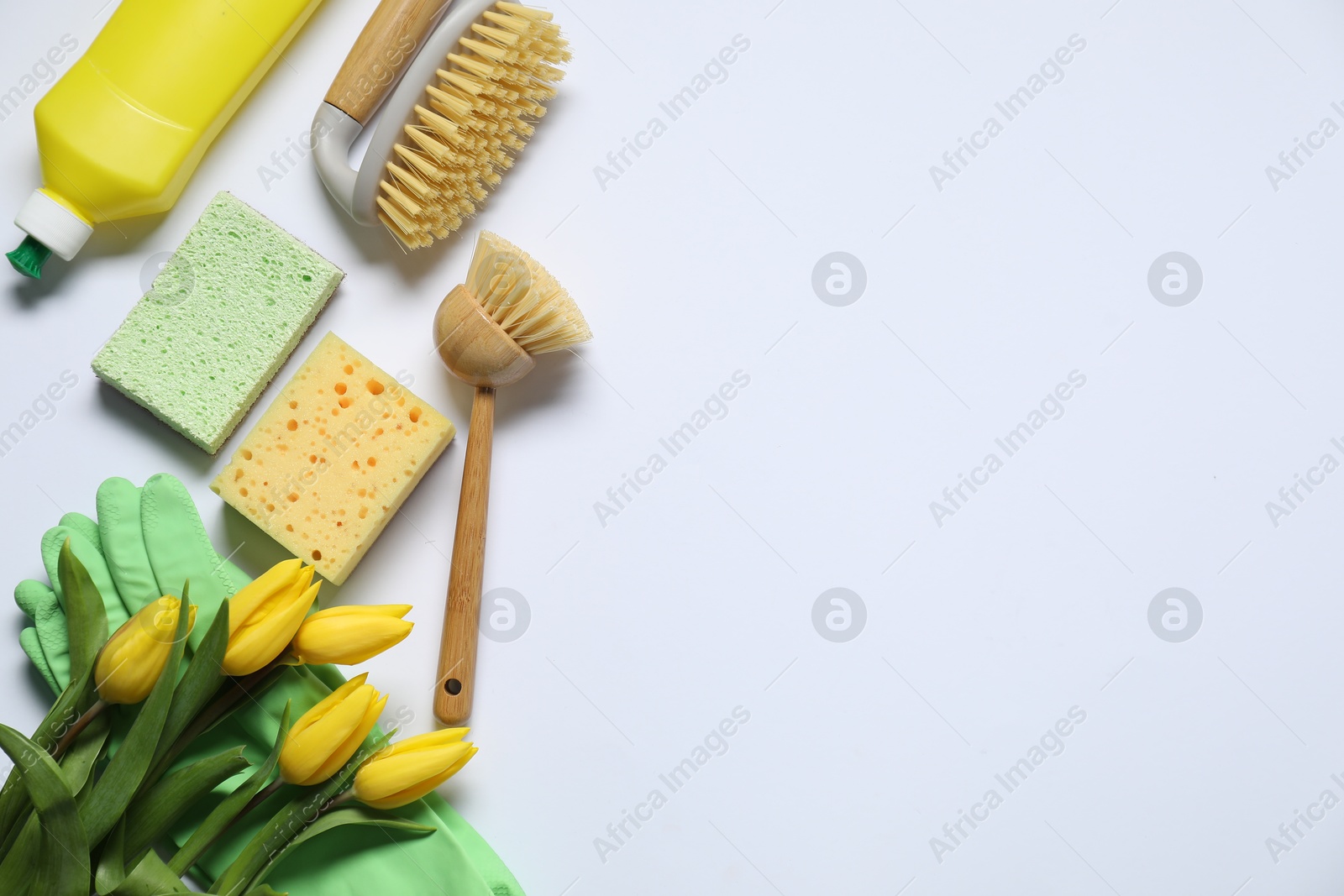 Photo of Spring cleaning. Detergent, supplies and tulips on white background, flat lay. Space for text