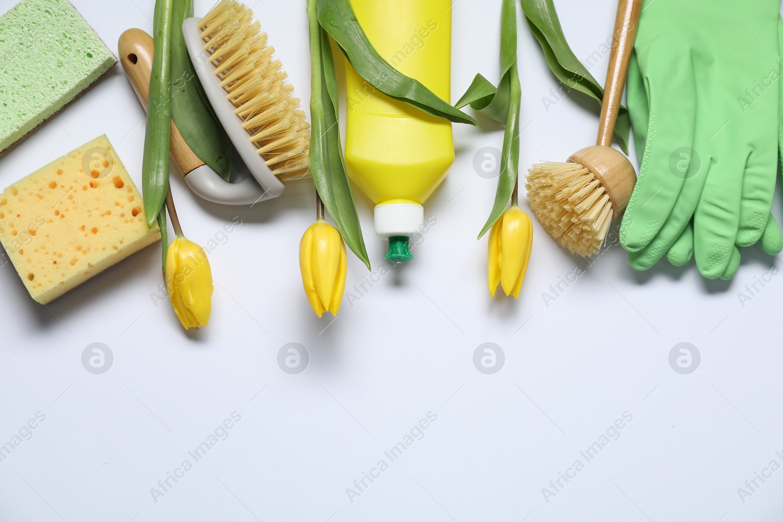 Photo of Spring cleaning. Detergent, supplies and tulips on white background, flat lay. Space for text