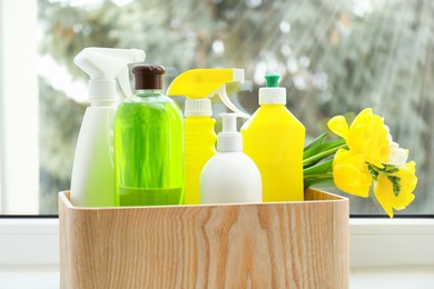 Photo of Spring cleaning. Detergents, supplies and flowers on windowsill indoors, closeup