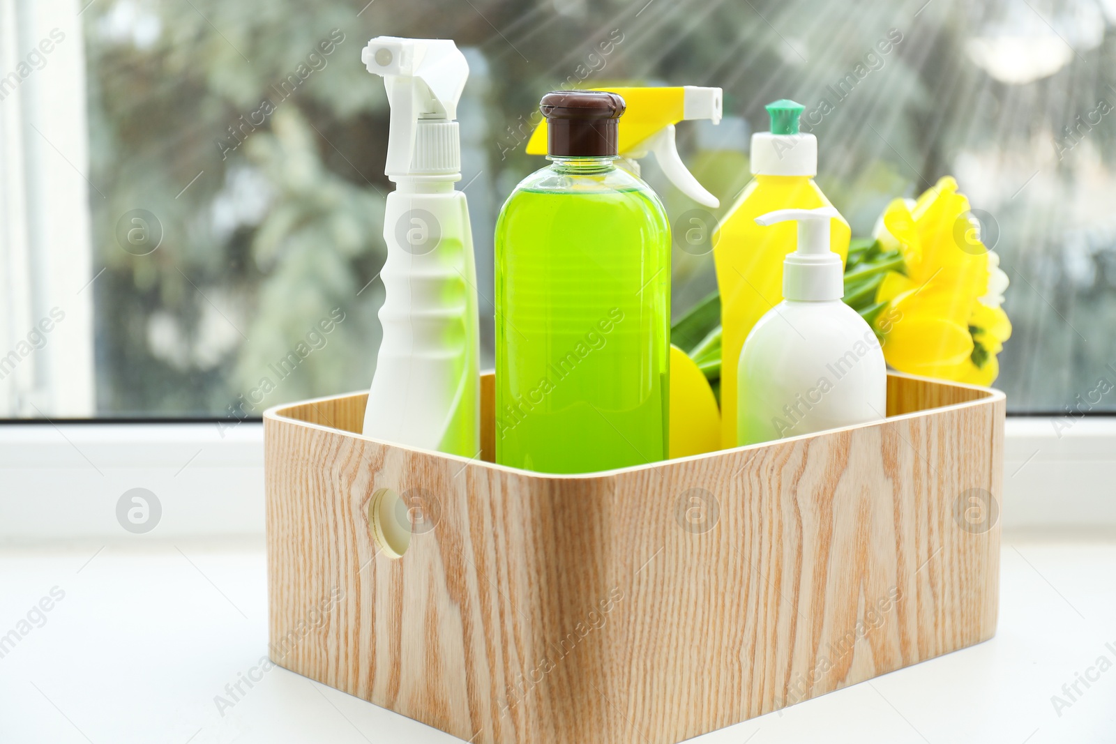 Photo of Spring cleaning. Detergents, supplies and flowers on windowsill indoors