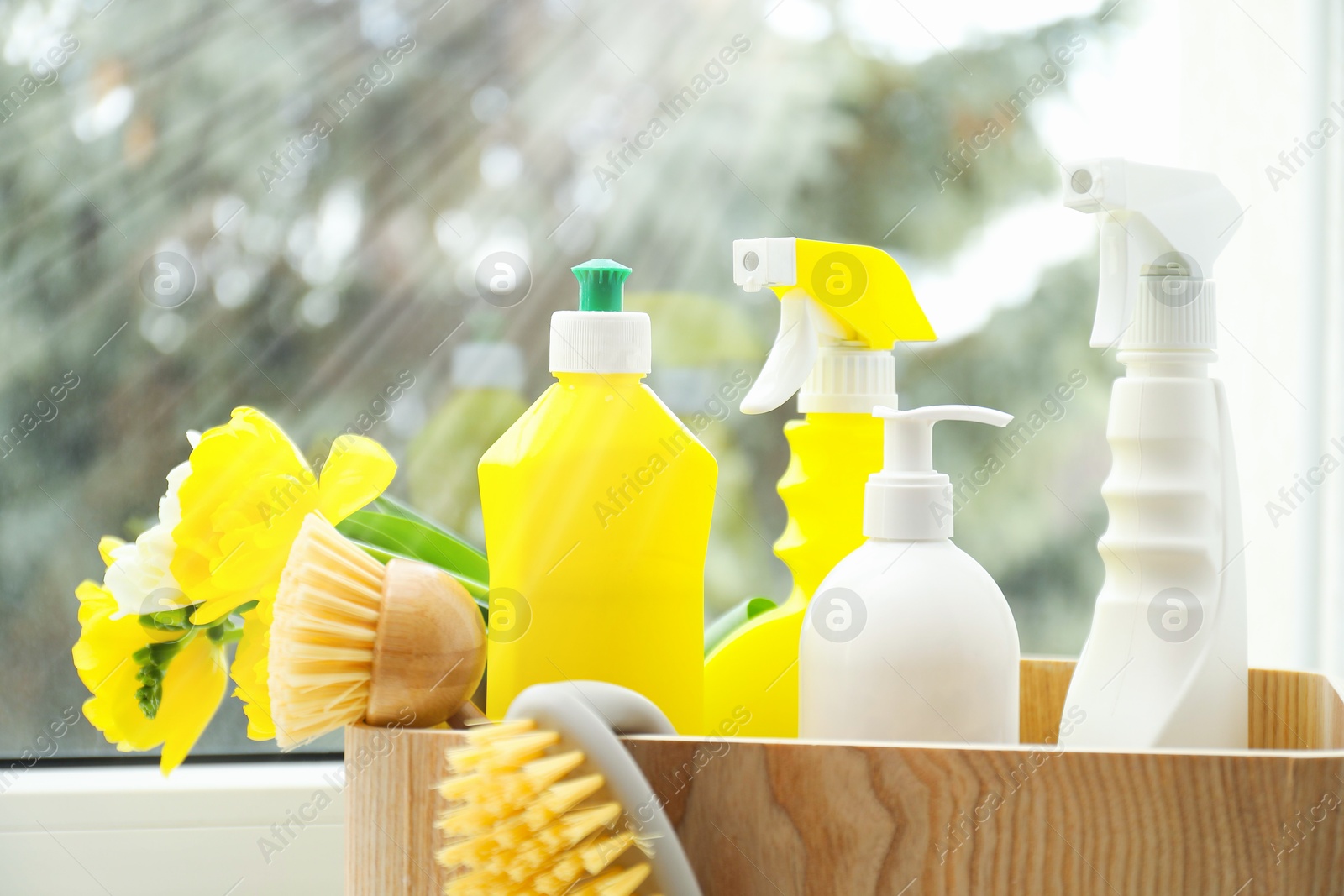 Photo of Spring cleaning. Detergents, supplies and flowers on windowsill indoors, closeup