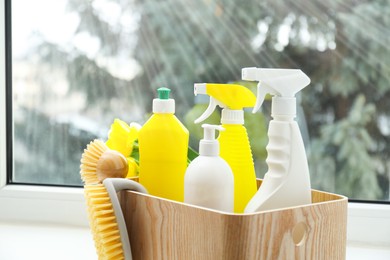 Photo of Spring cleaning. Detergents, supplies and flowers on windowsill indoors, closeup