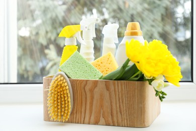 Photo of Spring cleaning. Detergents, supplies and flowers on windowsill indoors