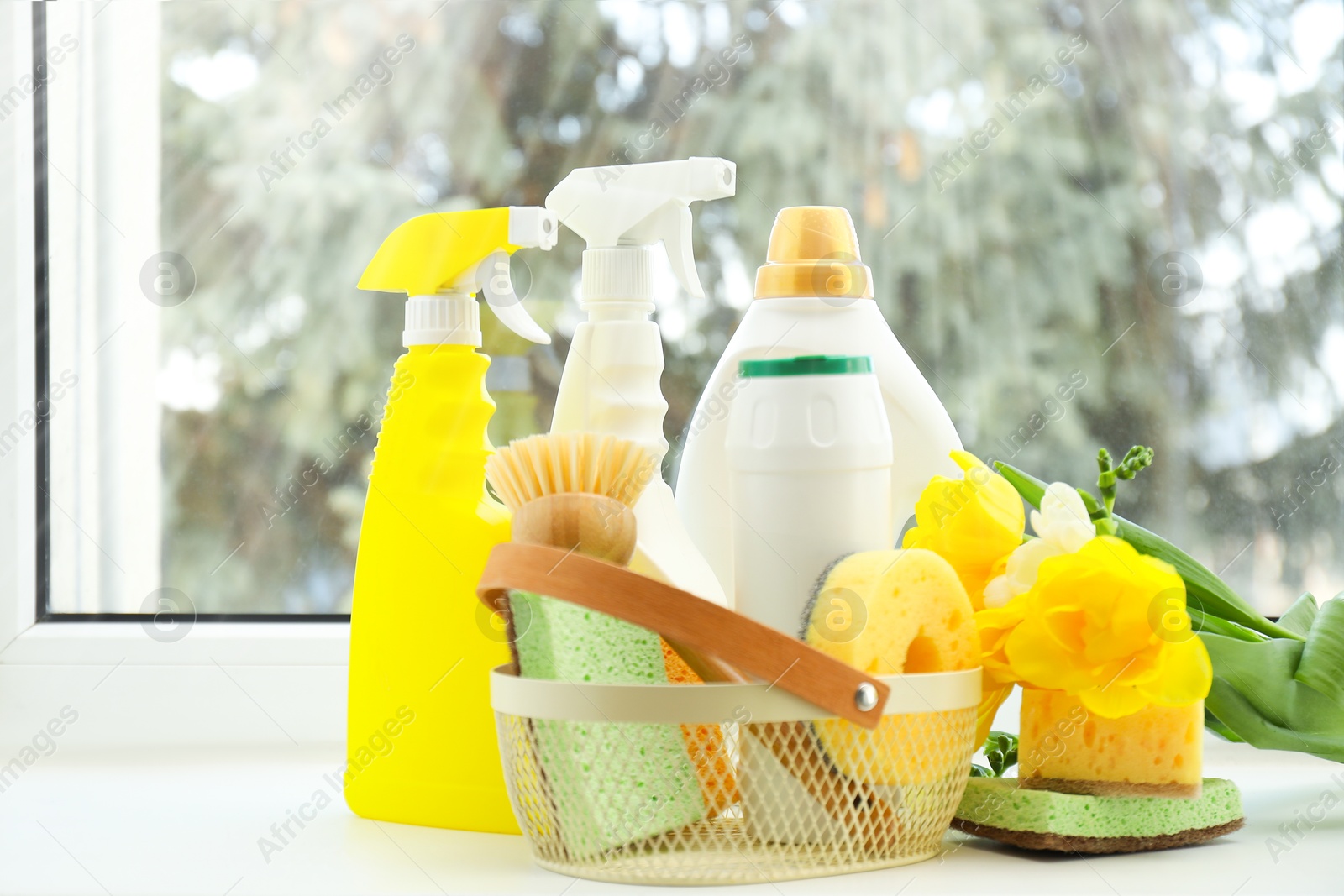 Photo of Spring cleaning. Detergents, supplies and flowers on windowsill indoors