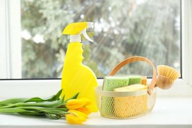 Photo of Spring cleaning. Detergents, supplies and tulips on windowsill indoors