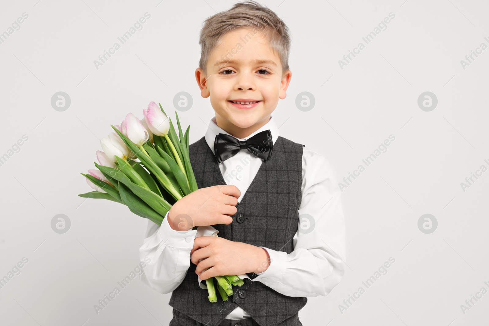 Photo of Cute little boy with bouquet of tulips on white background