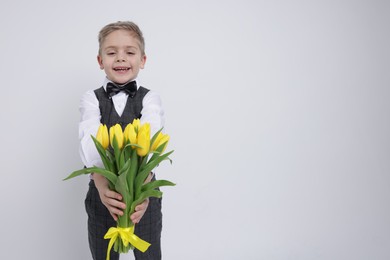 Cute little boy with bouquet of tulips on white background. Space for text