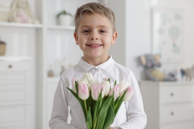 Photo of Cute little boy with bouquet of tulips at home