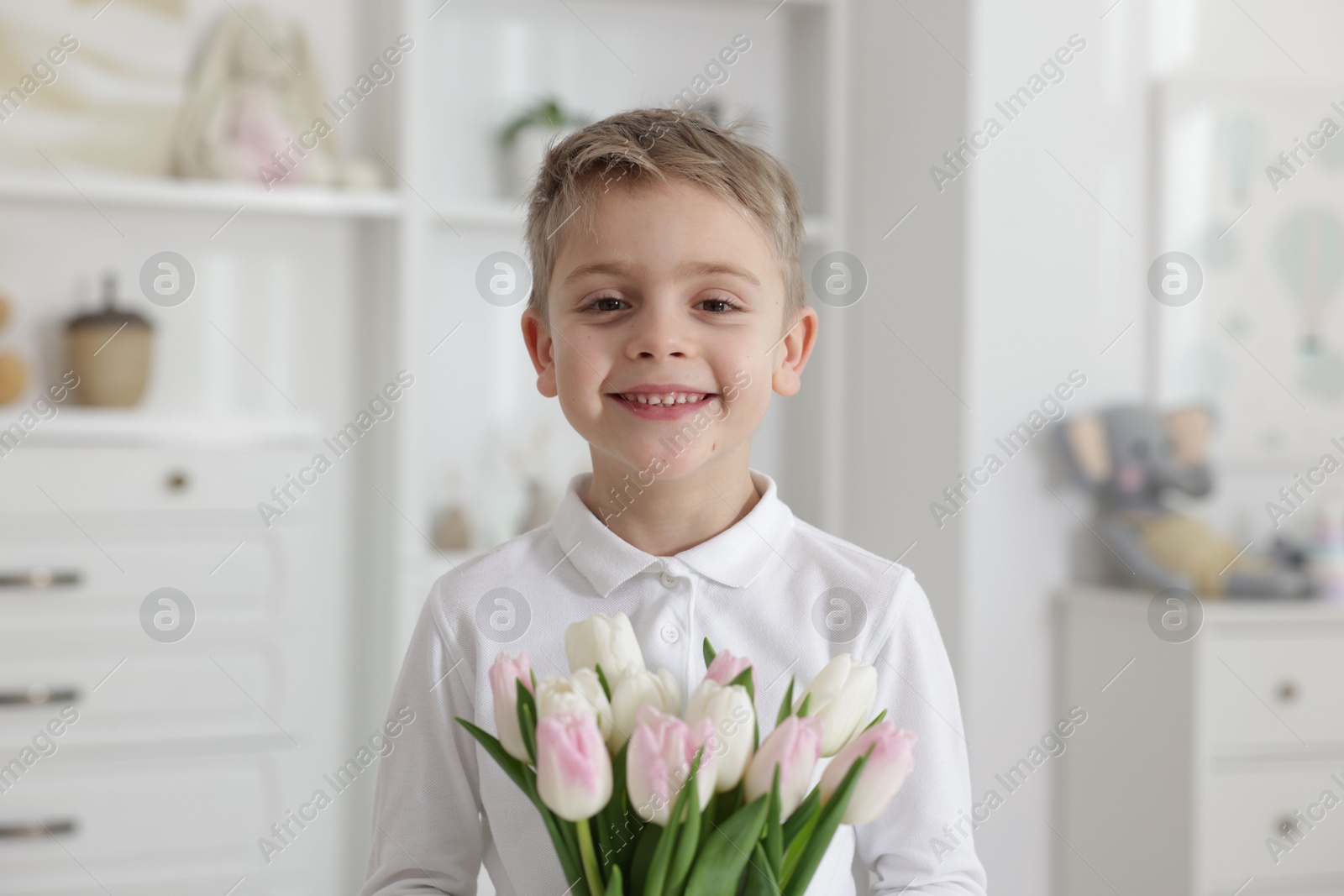 Photo of Cute little boy with bouquet of tulips at home